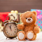 Alarm clock and teddy bear on christmas background