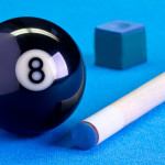 Billiard pool game eight ball with chalk and cue on billiard table with blue cloth