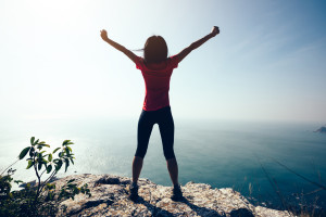 freedom female standing  with outstretched arms on sunrise windy coast