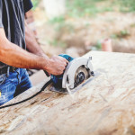 Industrial worker Using Circular Saw on wooden board in Carpentry Workshop