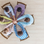 Coworkers stacking hands sitting at the office table