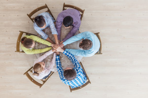 Coworkers stacking hands sitting at the office table