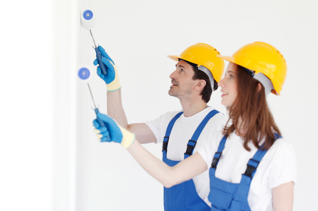 Team of young workers in hardhats painting the wall