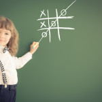 School kid in class. Happy child against green blackboard. Education concept