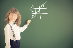 School kid in class. Happy child against green blackboard. Education concept